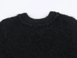 Close-up of black fuzzy knit sweater neckline with delicate beaded and sequin embellishments