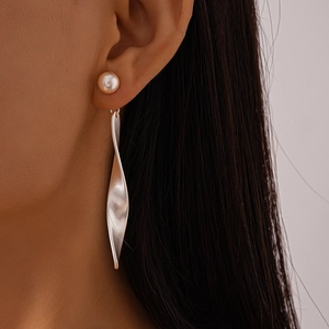 Side view of a silver twisted leaf earring with a white pearl on a female model