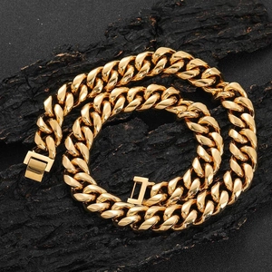 Polished gold Cuban link necklace with secure box clasp on a textured black bark surface