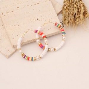 Detail of colorful Bohemian hoop earrings with Heishi beads and pearls on stone decor