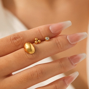 Titanium steel gold earring set with zircon studs shown on finger for scale