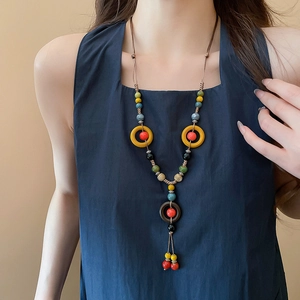 Detailed shot of ethnic ceramic bead necklace with wooden rings on a blue sleeveless top