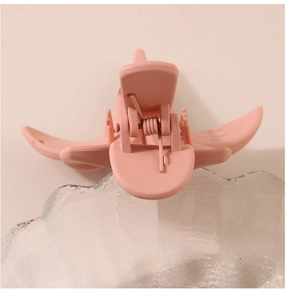 Détail de la pince à cheveux fleur rose mat montrant son ressort et ses dents de maintien