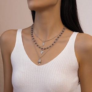 Detailed view of western style layered silver necklace with bull skull and cowboy hat charms