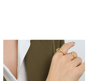 Close-up of gold-plated knot and chain ring set on model wearing green blazer