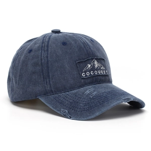 Close-up of embroidery patch on distressed navy blue washed denim baseball cap