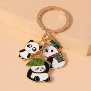 Detail of a golden metal keychain with vivid enamel panda charms and green bamboo leaf