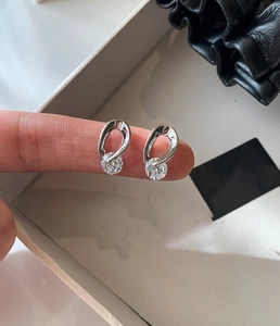 Detail of silver drop stud earring with hollow heart design and a round cubic zirconia
