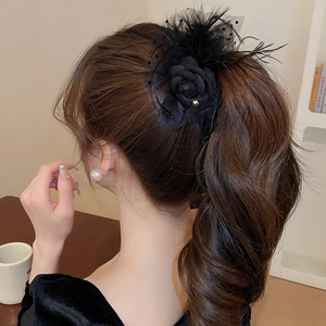 Elegant black ribbon hair clip with delicate feathers and mesh details worn on high ponytail