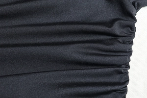 Detailed close-up of black elastic knit fabric with stylish side ruching design