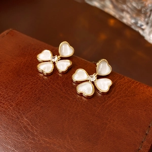 Detailed macro view of gold-plated heart-shaped petal earrings with zircon and shell inlay