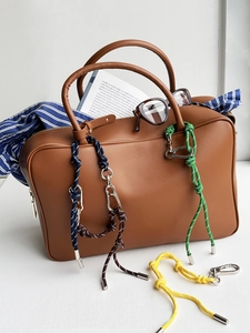 Detail van kleurrijke gevlochten touwsleutelhangers met karabijnhaken aan leren tas
