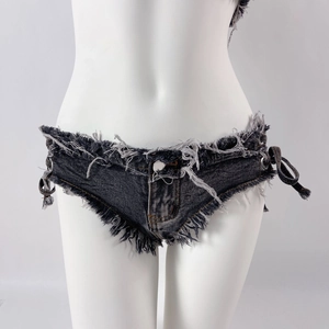 Dettaglio di pantaloncini in denim a vita bassa con frange rovinate e lacci metallici laterali