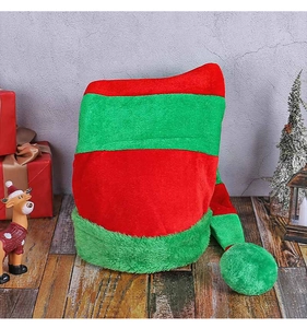 Christmas elf hat with red and green stripes on a rustic wooden background with festive decor