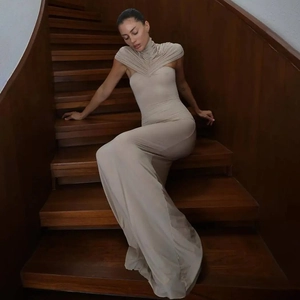 Detail van elegante beige nauwsluitende maxi-jurk met hoge hals en geplooide lijfje textuur