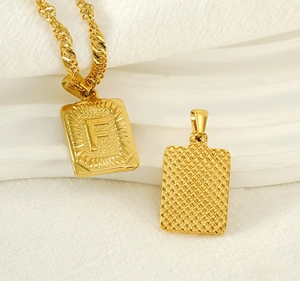 Macro detail of gold stainless steel necklace with engraved square letter F pendant