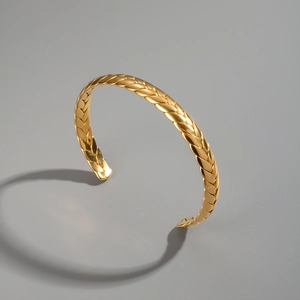 Vista dettagliata del bracciale rigido dorato minimalista con trama a chicco di grano