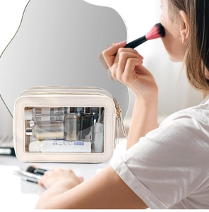 Lifestyle shot of a cream PU double-layer travel makeup bag with clear window panel
