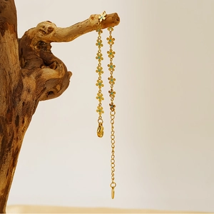Detailed view of gold daisy floral bracelet with blue centers on a wooden branch background