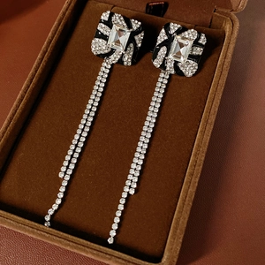 Close-up of square fringe earrings with black enamel and zircons on velvet box