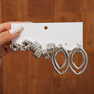 Detail of 3-pair silver earring set featuring knot studs, twisted hoops, and teardrop drops