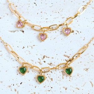 Macro shot of 18K gold plated heart necklaces with pink and green gemstone charms