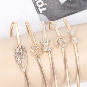 Détail de cinq chaînes de taille à ressort dorées avec boucles en strass sur support