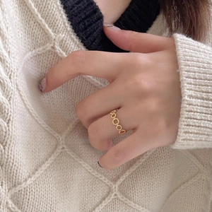Elegant gold-plated hollow beaded ring for women shown on hand with knitwear background