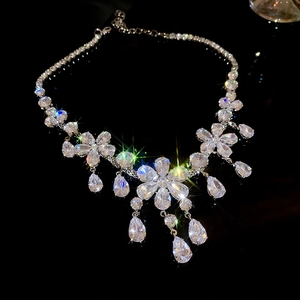 Macro view of flower cluster necklace with teardrop zircon pendants on black surface