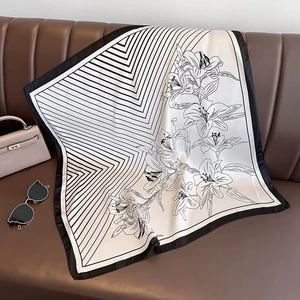 Flat lay of striped silk scarf with floral patterns on leather sofa with handbag