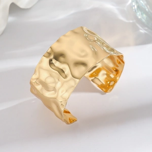 Close-up of wide gold-colored gingko leaf cuff with hammered texture and ruffled design
