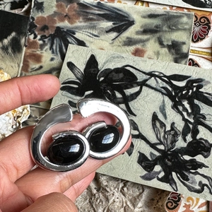 Detail of silver spiral ring with double black oval stones shown on an art card