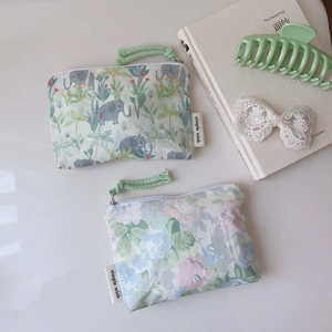 Détail de pochettes en coton à fleurs et éléphants avec étiquette et cordons de zip verts