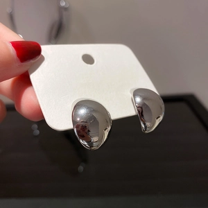 Close-up of minimalist silver teardrop stud earrings on a white display card