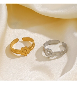 Detail showing minimalist gold and silver daisy flower rings on white silk fabric