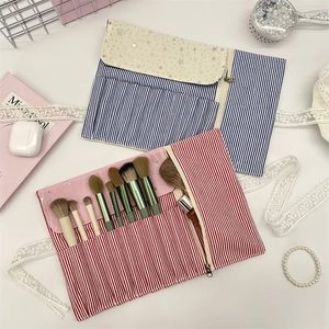Striped makeup brush set with storage roll bag, blush and eye brushes in a chic setup
