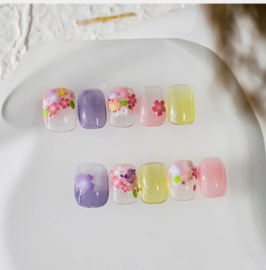 Close-up of floral press-on nails with cherry blossoms and bird patterns in pastel colors
