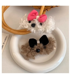 Detail of plush poodle hair clips in white and brown with cute bows in a ceramic dish