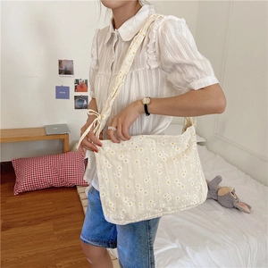 Close-up of vintage daisy print canvas shoulder bag on model in a cozy bedroom