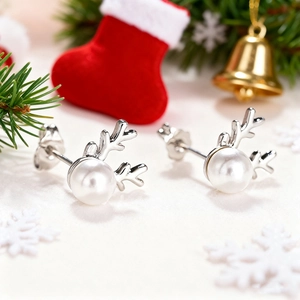 Detailed close-up of pearl reindeer antler earrings with festive Christmas decorations