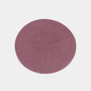 Detail of elegant dusty pink knitted beret showing concentric textures and metal logo