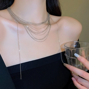Dettaglio della collana argentata a più strati indossata su un maglione nero