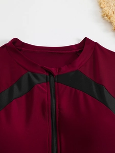 Détail du maillot de surf bordeaux avec rayures noires et fermeture éclair centrale