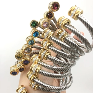 Detail of twisted cable stainless steel bracelets with colorful gemstones and gold accents