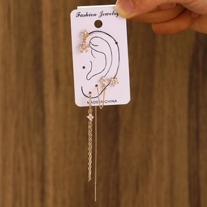 Detail of floral gold earring set with zircon accents and tassels on a card