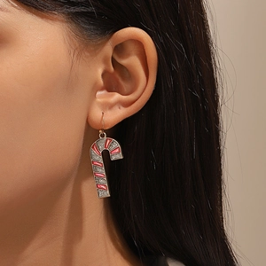 Detail of Christmas candy cane earrings with red and silver glitter worn by a model