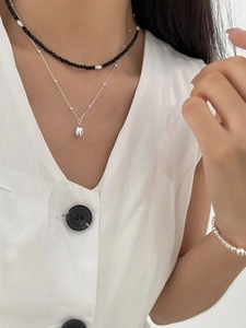 Close-up of layered S925 silver teardrop necklace and pearl beaded choker on model