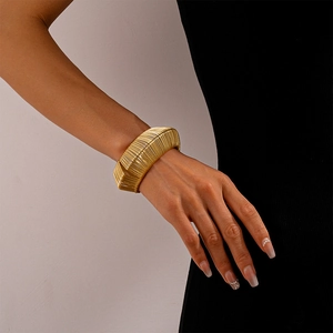 Detailed view of woven wide gold metal cuff bracelet on wrist for minimalist style