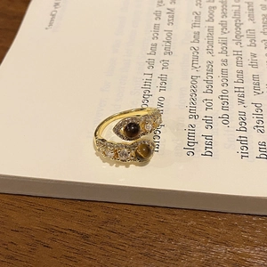 Detailed close-up of 18k gold plated tiger eye ring with zircons on a vintage book