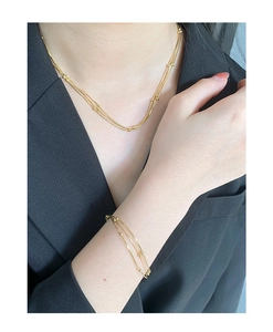 Nahaufnahme der dreilagigen goldenen Schlangenkette und des Perlenarmbands am Model